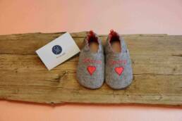 handgefertigter Krabbelschuh, Babyschuh, Hausschuh, Geschenk zur Geburt, aus weichem Wollfilz in hellgrau, abgefüttert mit Wildleder in rot, bestickt mit Herz und Spatzl, personalisierung möglich